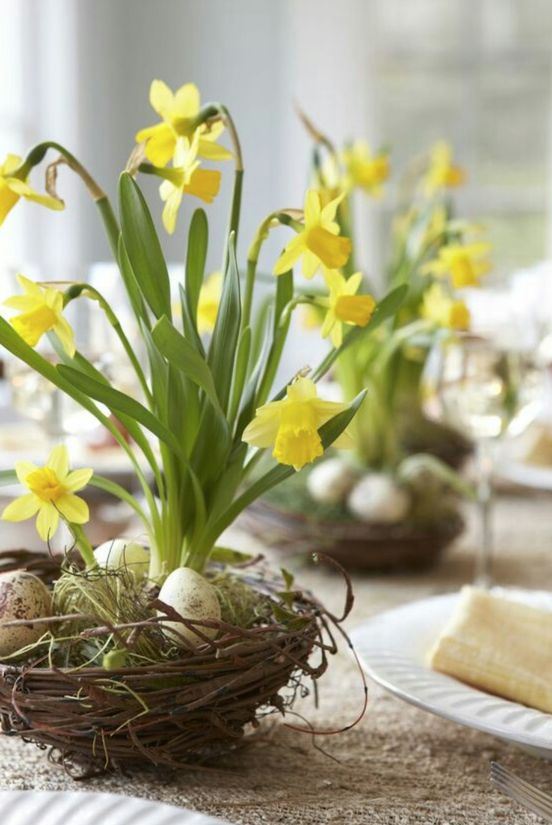 a chic spring centerpiece of a fake nest with eggs, moss and daffodils is an amazing idea for any table