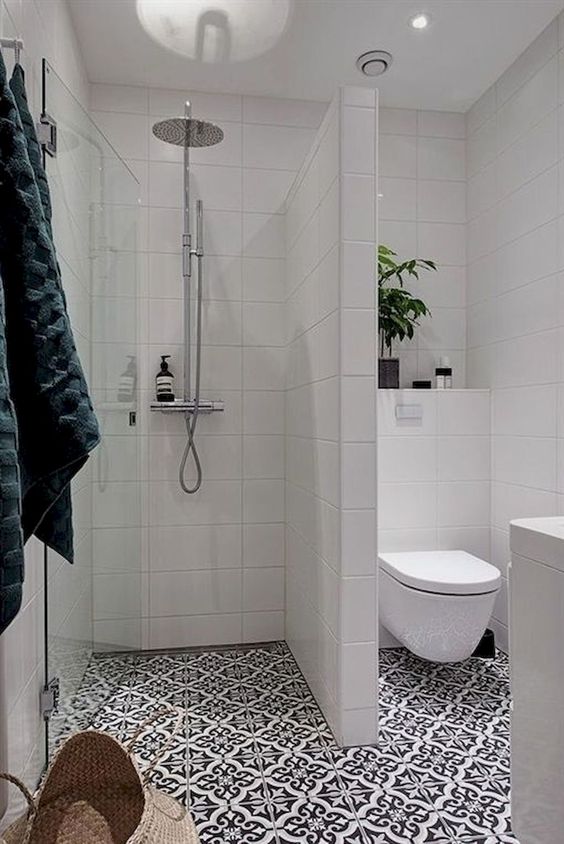 a contemporary bathroom with mosaic tiles, white tiles on the walls, potted greenery and a basket for storage
