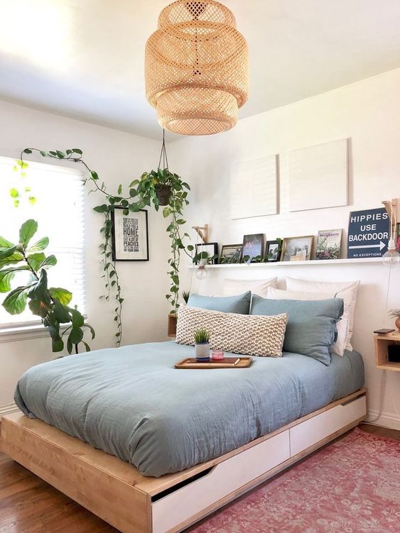 a contemporary small bedroom with a storage bed, a ledge with a gallery wall, a wicker lamp and potted greenery