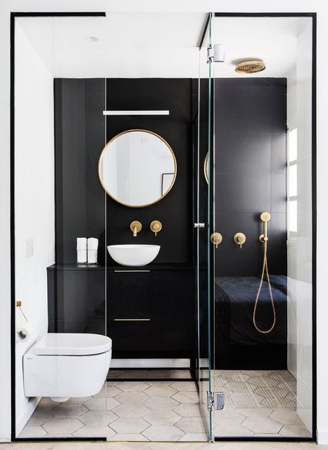 a contrasting small bathroom with a black statement wall and vanity, a shower, a round mirror and a bowl