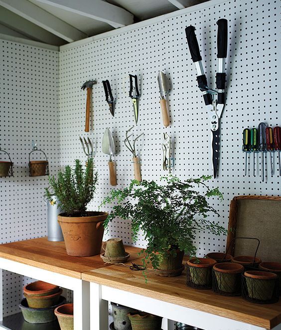 a couple of tables with shelves underneath and pegboard walls around are a contemporary option for storing everything in your shed