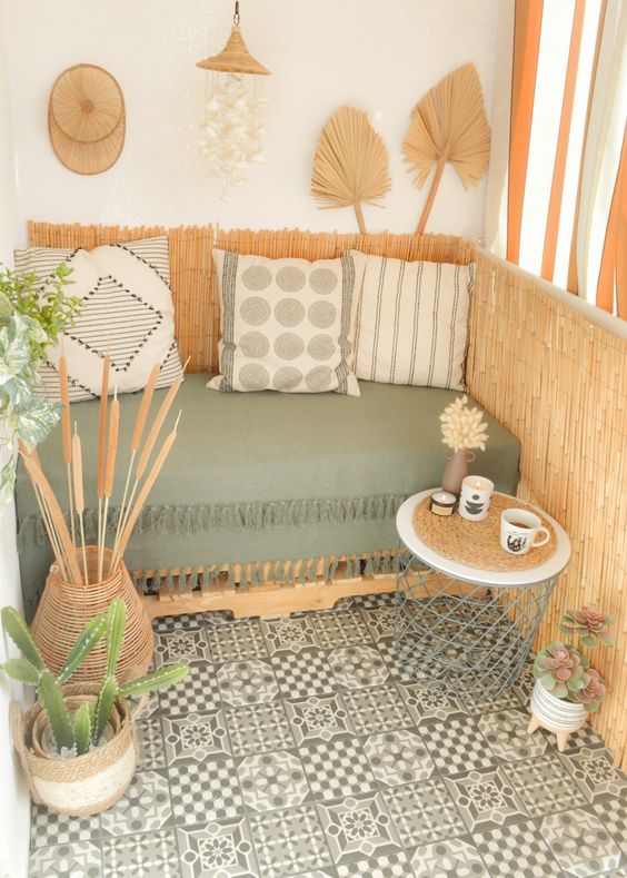a fab boho balcony with a pallet sofa with boho pillows, a side table, potted greenery and some boho decor like fronds is a very cool space