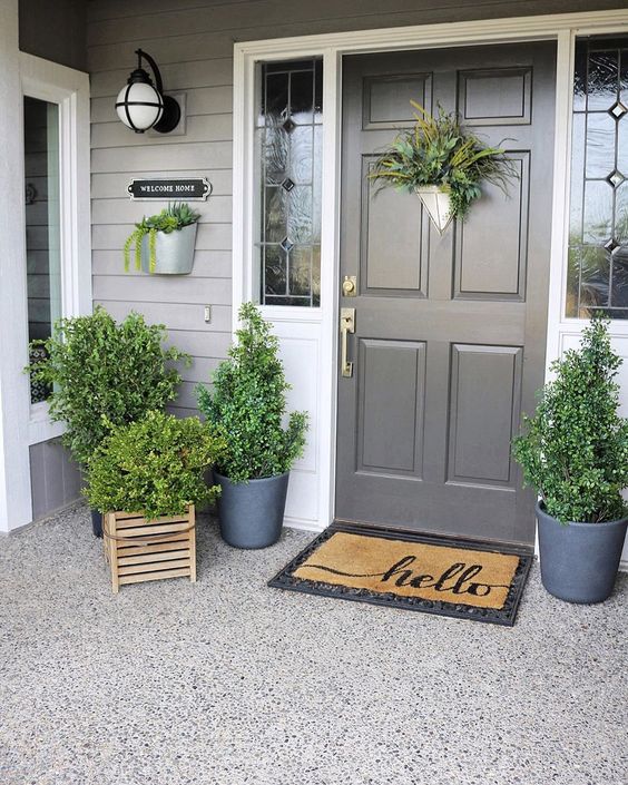 a fresh spring porch decorated only with greeneyr in pots and crates and with greenery on the door