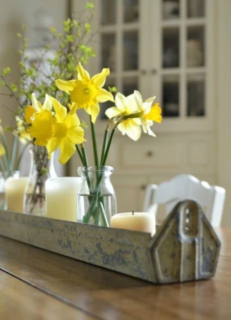 a galvanized long planter with candles, jars and vases and daffodils and blooming branches as a rustic spring centerpiece