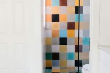 a modern bathroom clad with colorful tiles, with white appliances and a vanity that balance out the bold tiles