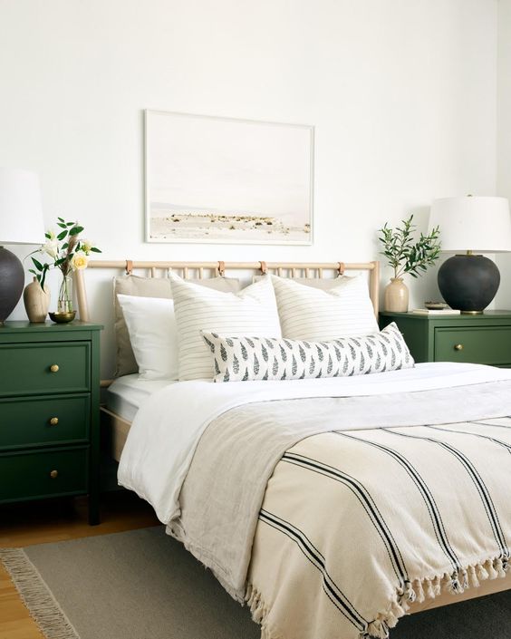 a modern spring bedroom with green nightstands, printed bedding, a neutral artwork and greenery