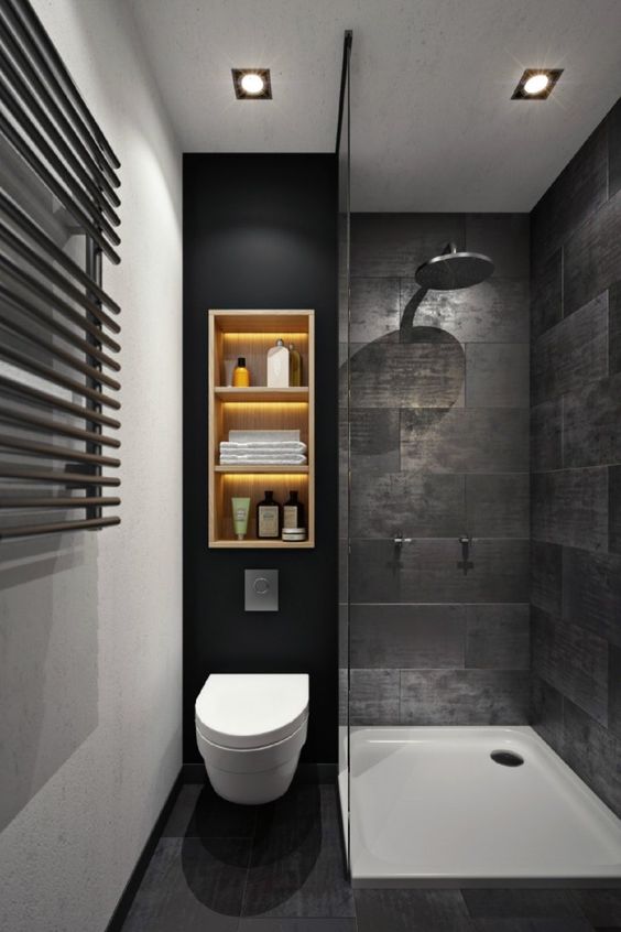 A moody black bathroom with stone inspired tiles, a wall shelf with lights, a shower space