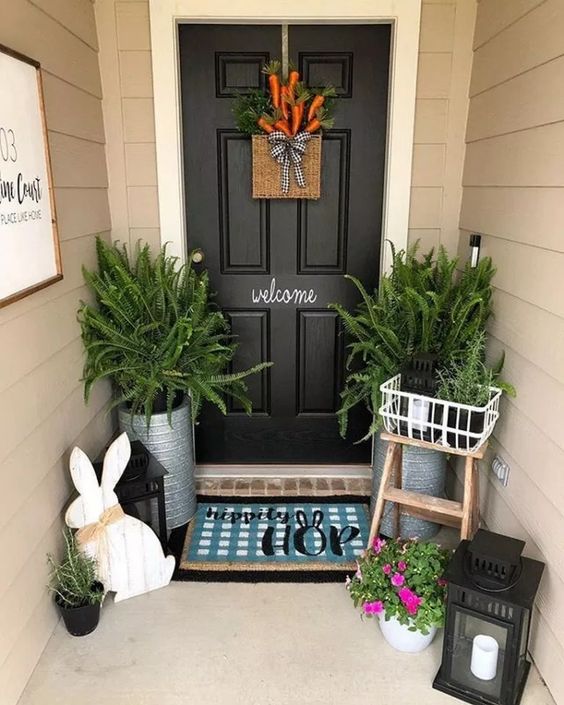 a plaque bunny, candle lanterns, potted ferns, a fake carrot door decoration and a bright printed rug