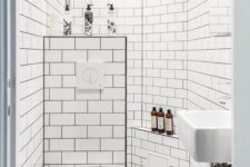 a retro-inspired black and white bathroom with a shower space, a mosaic tile floor and a half wall