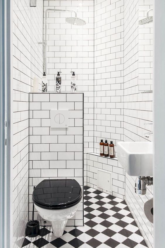 A retro inspired black and white bathroom with a shower space, a mosaic tile floor and a half wall