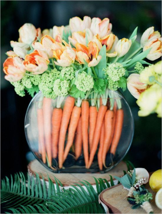a round aquarium with frehs carrots and matching orange tulips is a bold spring or Easter decoration