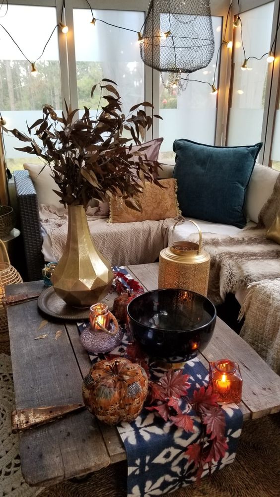 a screened boho porch with a sectional with neutral layered textiles, colorful fall table styling, touches of gold and lights