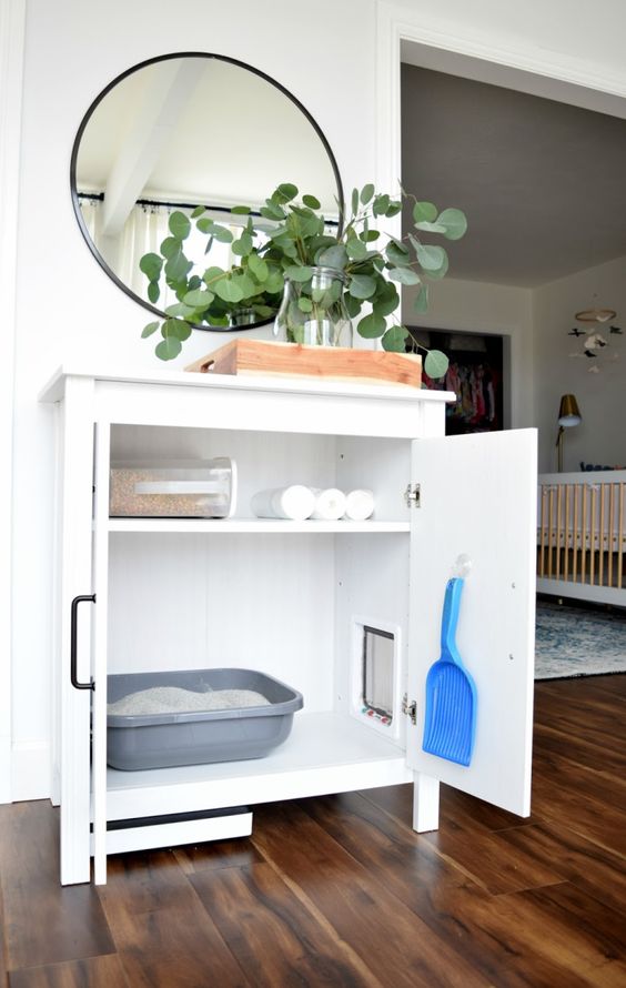 a simple and neutral white cabinet with a cat litter box inside and everything necessary inside it, too