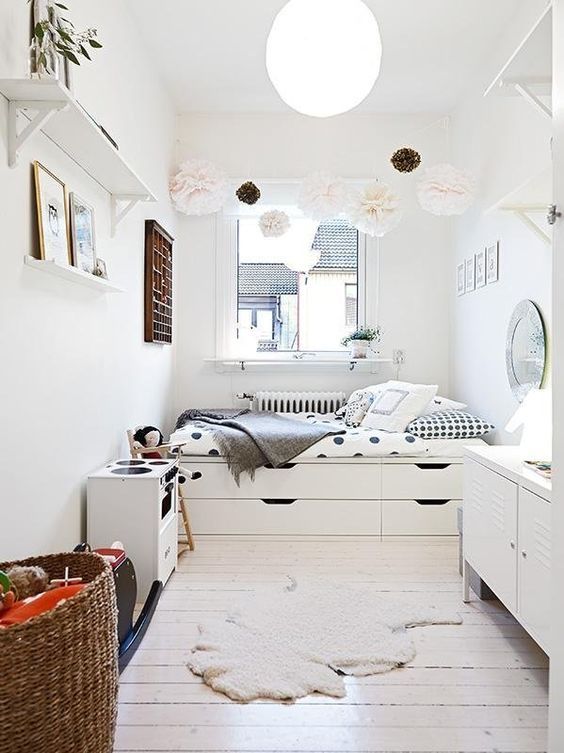 a small Nordic bedroom with a storage bed, a pompom garland, storage units and open shelves