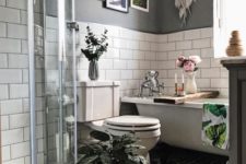 a small boho bathroom with grey and white subway tile walls, a shower space, a gallery wall and potted greenery