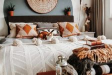 a small boho bedroom with a black bed, a Moroccan lamp, a wooden bench and potted plants here and there