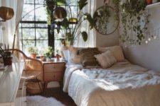 a small boho bedroom with cascading greenery in pots, wooden furniture and brass lamps
