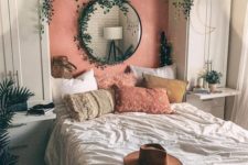 a small boho bedroom with white wardrobes and a built-in bed, lots of cascading greenery, boho pillows and lights