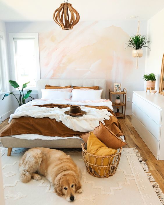 a small modern bedroom with a watercolor wall, a sleek white dresser, an upholstered bed and a wooden lamp, potted plants