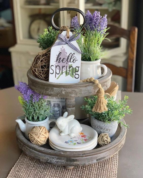 a spring kitchen stand with purple blooms, vine balls, greenery, bunnies and floral plates