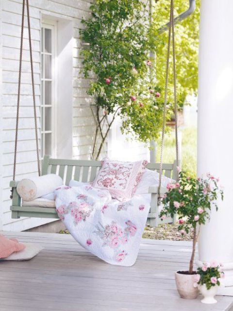 a spring terrace with a suspended daybed, floral bedding, potted blooms and greenery is airy and welcoming