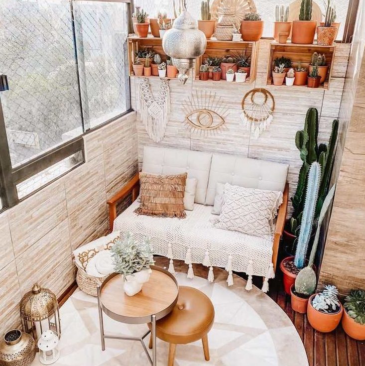 a stylish boho balcony with open shelves with lots of plants and potted succulents and cacti, a sofa with boho pillows, side tables and poufs is cool