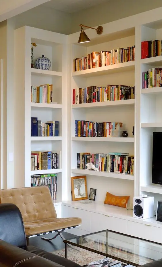 a stylish mid-centrury modern living room with built-in bookshelves and additional lamps over the space