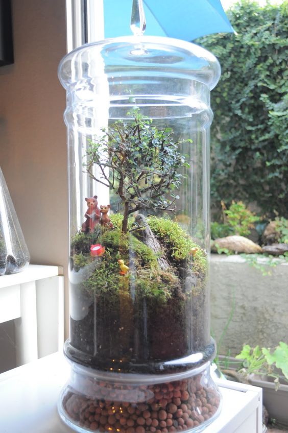 A tall jar with a scenery   moss hills, a mini tree, wood and bears and a duck is a cute idea for a child's room