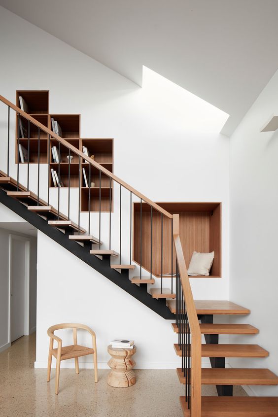 A wall with built in bookshelves and a niche seat is a genius idea to rock over the stairs