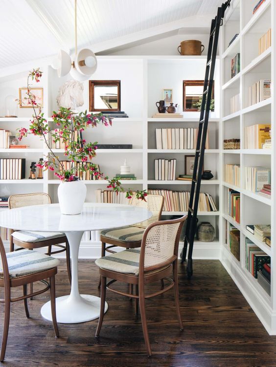 A welcoming mid century modern dining space with built in bookshelves, a round table and rattan chairs
