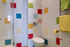 a white bathroom with a neon green floor and with bright tiles accenting the walls and colorful towels is amazing