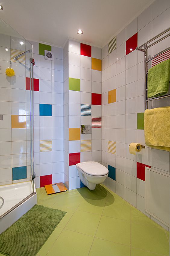 a white bathroom with a neon green floor and with bright tiles accenting the walls and colorful towels is amazing