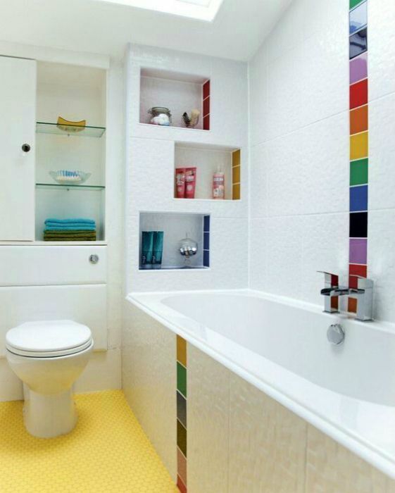 A white bathroom with colorful tiles accenting the walls and shelves, a yellow floor and a skylight is a pretty and mood raising idea