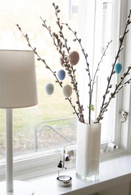 a white vase with willow and colorful and pastel eggs hanging on them will be a nice Easter decoration