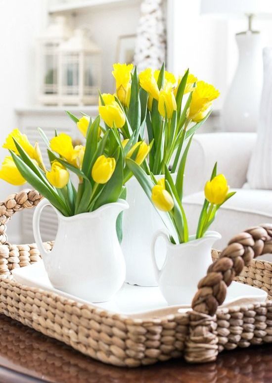a wicker tray with several matching white jugs and bright yellow tulips for a bold springy look