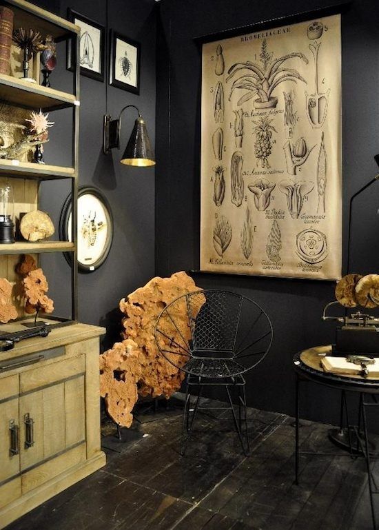 an elegant Gothic home office with black walls, a rustic wooden storage unit with open shelves, a vintage poster and metal furniture