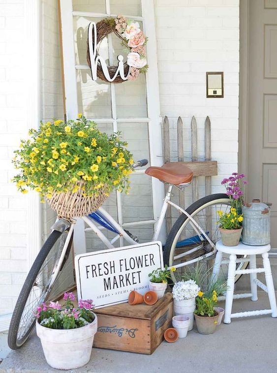colorful potted and basket blooms, a fake flower wreath and a watering can for a spring porch