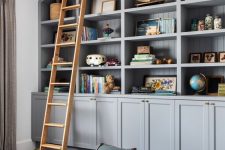 grey built-in bookshelves, blue poufs and a ladder to get all the books comfortably