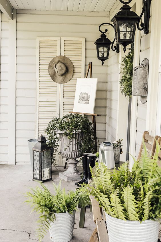 potted greenery and a greenery wreath plus some vintage stuff and lanterns for an elegant spring porch