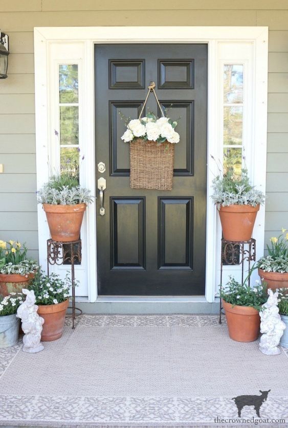 potted greenery and blooms, a basket with white flowers and some bunny statuettes for a farmhouse spring porch