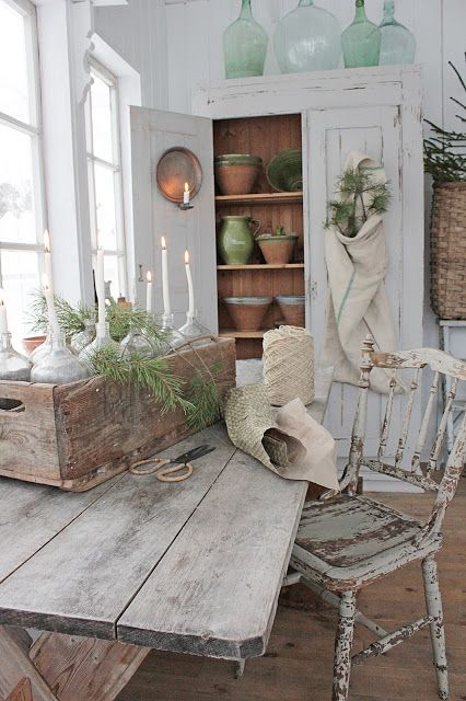 a Scandinavian farmhouse space with a whitewashed storage cupboard, a whitewashed table and a whitewashed and distressed chair