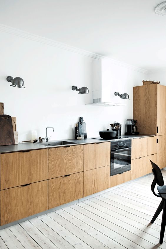 a Scandinavian kitchen with white walls, a whitewashed floor and wooden cabinets plus a concrete countertop
