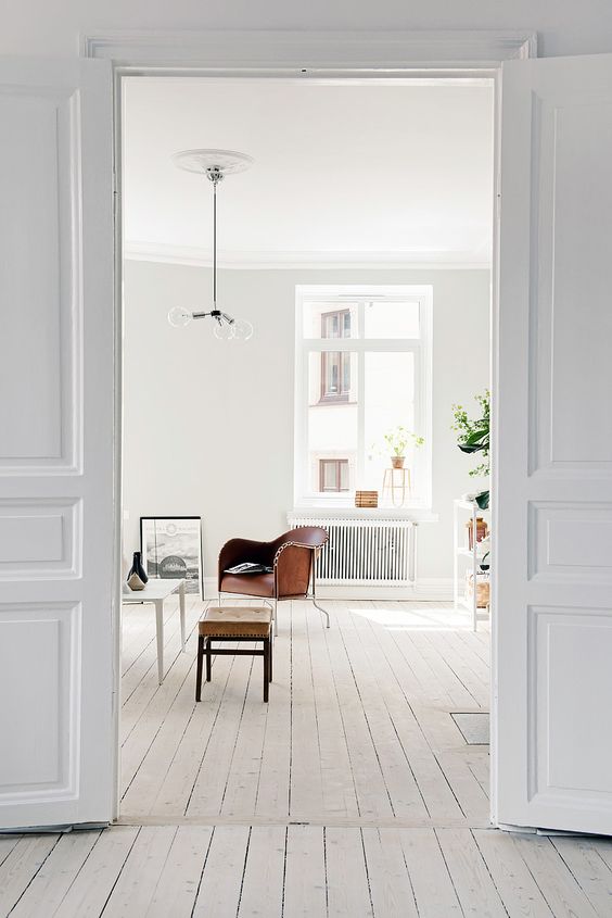 a Scandinavian space with white walls, a whitewashed floor, a white ceiling and leather furniture