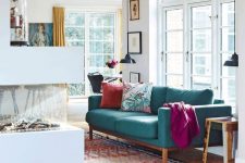 a contemporary living room with a fireplace, a turquoise sofa and bright textiles, pendant lamps and printed mini rugs