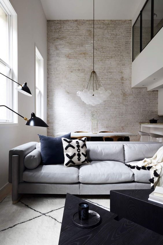 a contemporary living room with a whitewashed wall, chic furniture, a cluster chandelier and black for a touch of drama