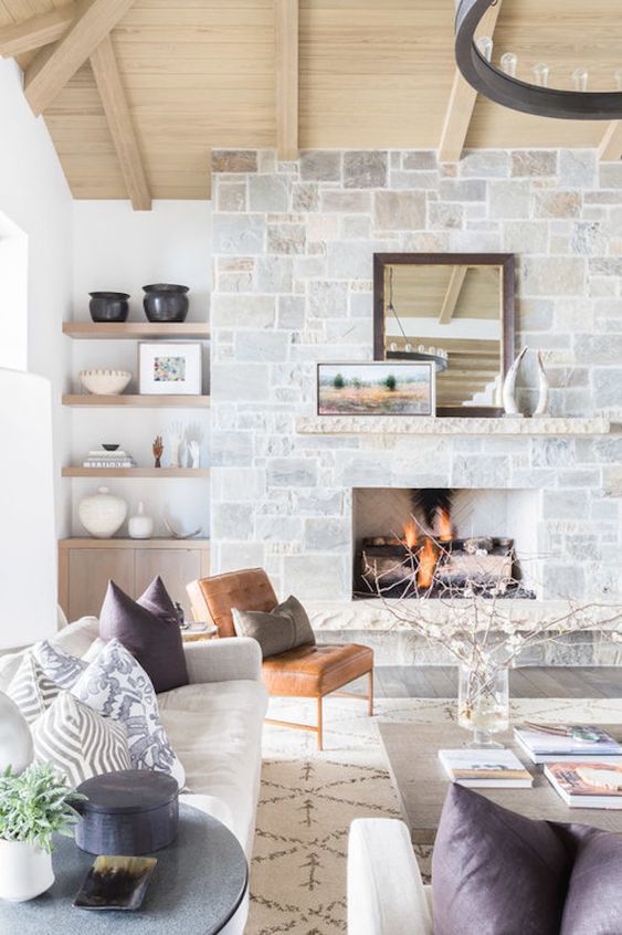 a cozy whitewashed stone fireplace with mantels, vintage decor on the mantel makes the space very wlecoming