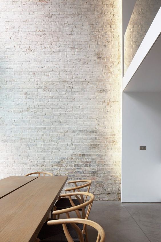 a minimalist dining room with a whitewashed brick wall that brings more interest and catchiness to the space
