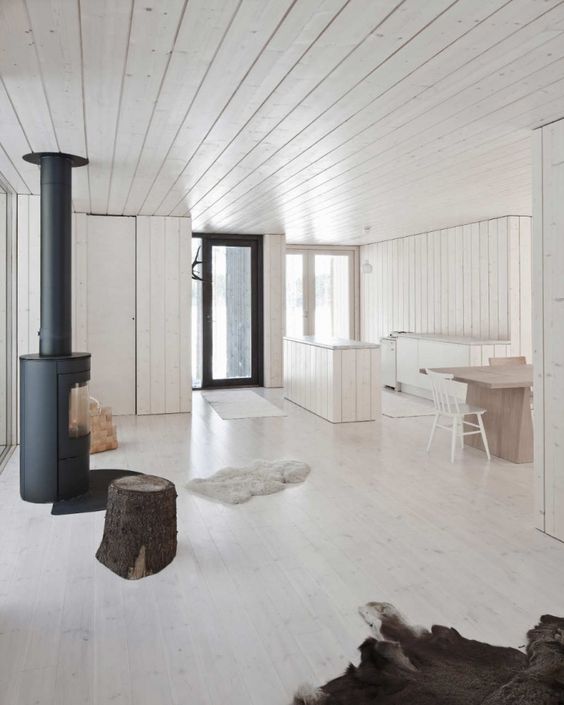a minimalist space with whitewashed walls, a ceiling, a floor and wooden furniture and a hearth