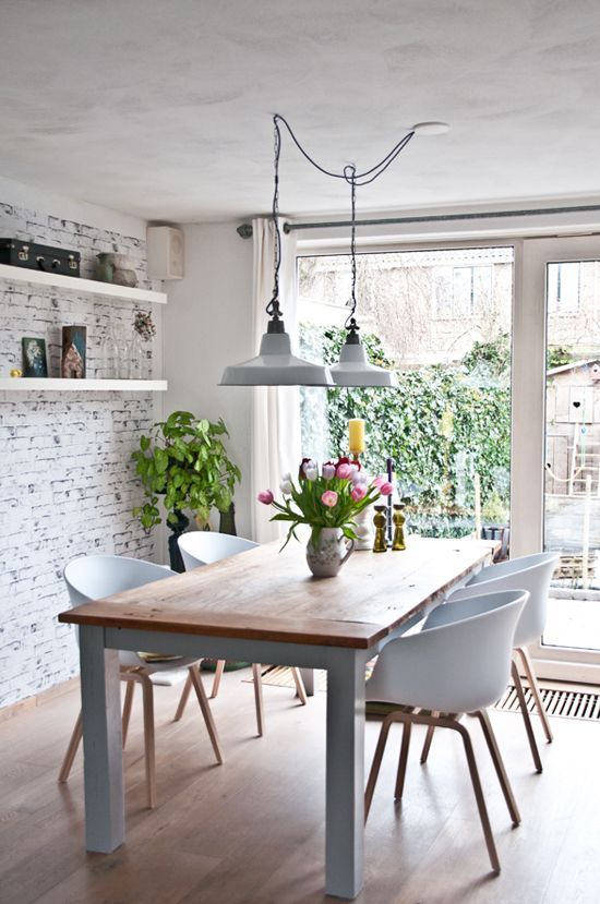 a modern Nordic dining room with a whitewashed brick wlal, a modern dining set and vintage lamps and potted plants