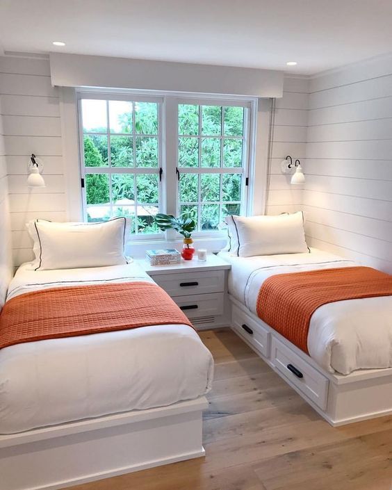 a modern farmhouse guest bedroom with whitewashed wooden walls, neutral furniture, wall sconces and a large window